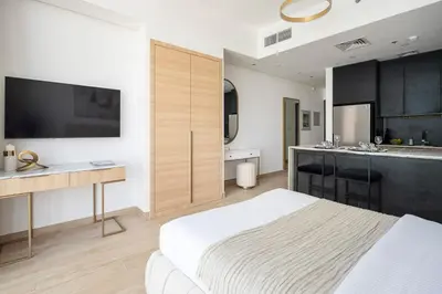 a bedroom with a large bed and a kitchen at Frank Porter - Regina Tower in Dubai