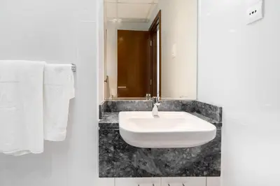 a white sink in a bathroom with white towels at White Sage - Amna Tower in Dubai
