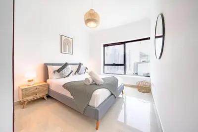 a white bedroom with a bed and a window at Spacious 3BR with 180˚ Dubai Marina Views in Dubai