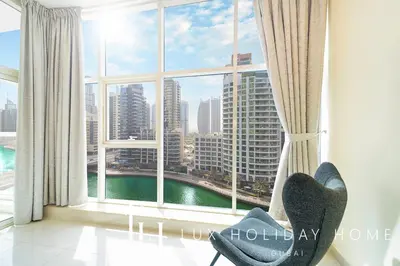 a chair in front of a window with a view of a city at LUX Marina View Prime Location Near Beach in Dubai