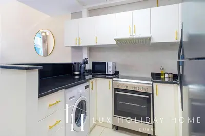 a kitchen with white cabinets and a washer and dryer at LUX Marina View Prime Location Near Beach in Dubai