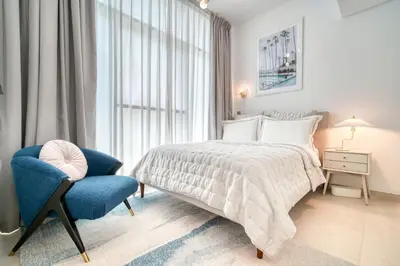 a white bedroom with a bed and a blue chair at Studio with City Views, Jumeirah Lake Towers - Mint Stay in Dubai