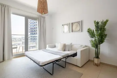 a white living room with a couch and a potted plant at Frank Porter - Grand Horizon in Dubai