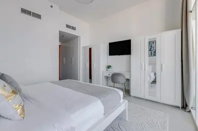 a white bedroom with a bed and a desk at GlobalStay Azizi Mina Beachfront Apartments Palm Jumeirah in Dubai