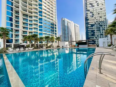 a large swimming pool with palm trees and buildings at HiGuests - Roomy and Chic Studio with Panoramic Canal Views in Dubai
