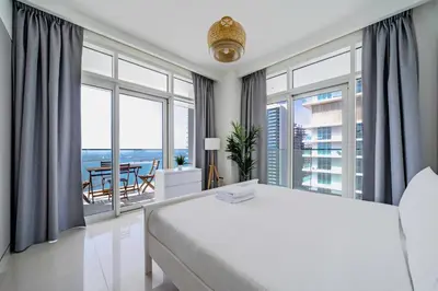 a bedroom with a large white bed and large windows at Breathtaking Atlantis view, Spacious 2BR on beach in Dubai