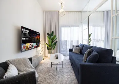 a living room with a blue couch and a table at First Class Apartments in Dubai Hills - Next to Dubai Hills Mall - Socio, Collective and Golfville Towers in Dubai