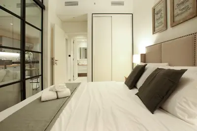 a bedroom with a large white bed with black pillows at First Class Apartments in Dubai Hills - Next to Dubai Hills Mall - Socio, Collective and Golfville Towers in Dubai
