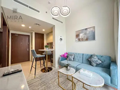 a living room with a blue couch and a table at Mira Holiday Homes - Newly furnished 1 bedroom in Business Bay in Dubai