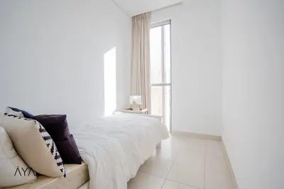 a white bedroom with a bed and a window at Luxury Apartment with Pool, Patio & Gym in City Walk By ĀYA Boutique in Dubai