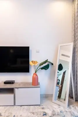 a living room with a tv and a mirror at The Smart Concierge - Waves by Kasco in Dubai