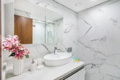 a white marble bathroom with a sink and a mirror at The Smart Concierge - Waves By KASCO in Dubai