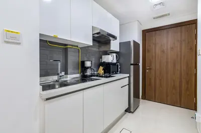 a kitchen with white cabinets and a wooden door at The Smart Concierge - Waves By KASCO in Dubai