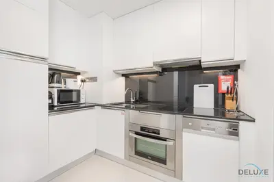 a kitchen with stainless steel appliances and white cabinets at Marina Canal Views Next to Mall & Marina Promenade Studio Unit, The Address Residences, Dubai Marina by Deluxe Holiday Homes in Dubai