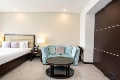 a bedroom with a bed and a blue chair and a table at Marina Canal Views Next to Mall & Marina Promenade Studio Unit, The Address Residences, Dubai Marina by Deluxe Holiday Homes in Dubai