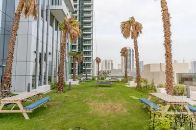 a park with benches and palm trees in front of a building at GuestReady - Zen in the heart of JVC in Dubai