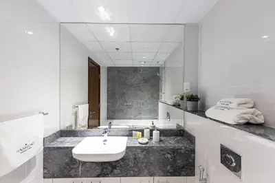 a white bathroom with a sink and a mirror at Hashtag Holiday Home - 1BDR Apartment with Canal View in Business Bay in Dubai