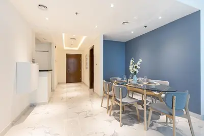 a dining room with a blue wall and a table and chairs at Hashtag Holiday Home - 1BDR Apartment with Canal View in Business Bay in Dubai