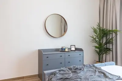 a bedroom with a dresser and a mirror on the wall at Hashtag Holiday Home - 1BDR Apartment with Canal View in Business Bay in Dubai