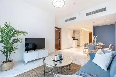 a living room with a blue couch and a tv at Hashtag Holiday Home - 1BDR Apartment with Canal View in Business Bay in Dubai