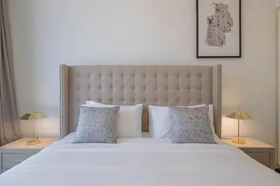 a bedroom with a large bed with white sheets and pillows at Hashtag Holiday Home - Excellent 1BDR with City View in Media city in Dubai