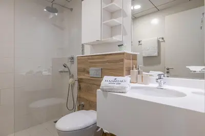 a white bathroom with a toilet and a sink at Hashtag Holiday Home - Excellent 1BDR with City View in Media city in Dubai