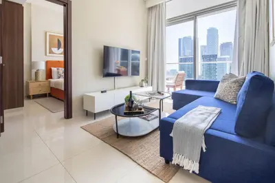a living room with a blue couch and a tv at Frank Porter - Vera Residence in Dubai
