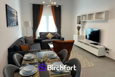 a living room with a couch and a table and a television at Birchfort - Newly renovated unique 1 bedroom apartment in Dubai