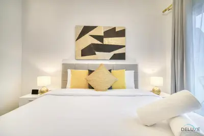 a bedroom with a large white bed with yellow pillows at Refined 1BR at Bella Rose Barsha South by Deluxe Holiday Homes in Dubai