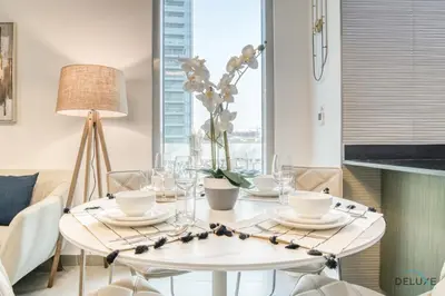 a white dining room table with chairs and a lamp at Refined 1BR at Bella Rose Barsha South by Deluxe Holiday Homes in Dubai