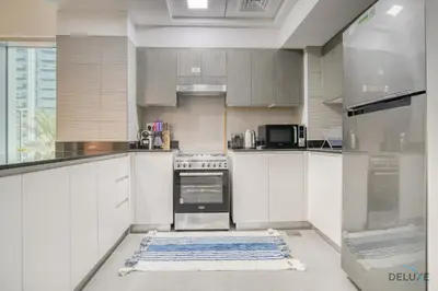 a kitchen with white cabinets and a blue rug on the floor at Refined 1BR at Bella Rose Barsha South by Deluxe Holiday Homes in Dubai