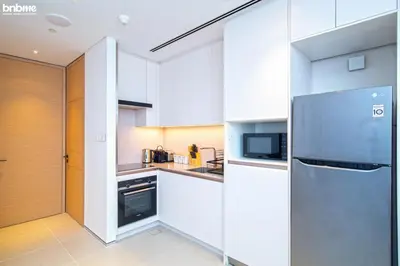 a kitchen with white cabinets and a stainless steel refrigerator at bnbme - Luxury 1BR Marina View Apt w Balcony Pool Gym Access Near JBR Beach & Walk in Dubai