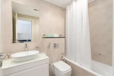 a bathroom with a sink and a toilet and a mirror at Gala Guests - Carson Studio Collection in Dubai