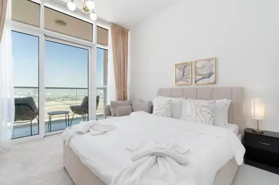 a white bedroom with a large bed and a large window at Gala Guests - Carson Studio Collection in Dubai