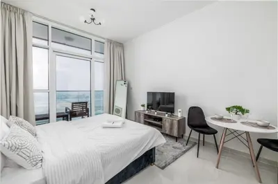 a white bedroom with a bed and a table and chairs at Gala Guests - Carson Studio Collection in Dubai