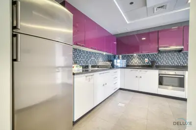 a kitchen with white cabinets and pink walls and a refrigerator at Sea Views from Living to Bedroom Perfect for Staycation, Dubai Marina by Deluxe Holiday Homes in Dubai