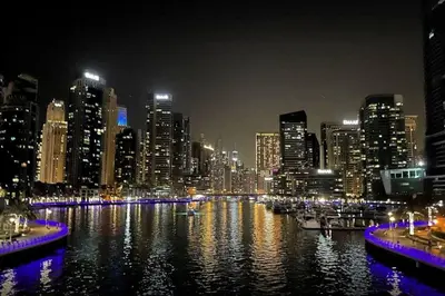 a city skyline at night with a river with boats at La Buena Vida Holiday Homes - Exquisite Spacious Luxe 1BR Apt , Full Marina View, Kitchen, 5 Min to Beach, JBR and Marina in Dubai