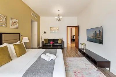 a bedroom with a large bed and a living room at La Buena Vida Holiday Homes - Modern, Luxe & Spacious 4-Bed, Full Kitchen, near to Beach, Tram & Marina in Dubai