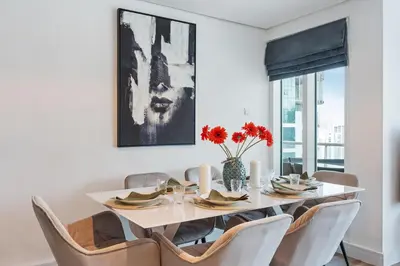 a dining room with a white table and chairs at Modern & Spacious 2-Bed Condo with Panoramic Lake Views, Dual Balconies, Steps from Dubai JLT Metro By 