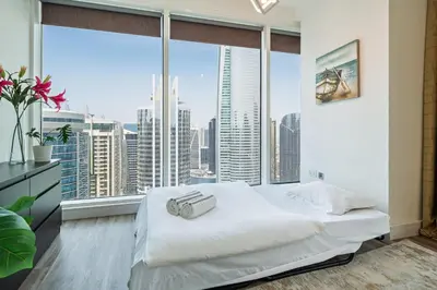 a bedroom with a white bed and a large window at Modern & Spacious 2-Bed Condo with Panoramic Lake Views, Dual Balconies, Steps from Dubai JLT Metro By 