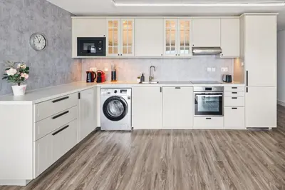 a kitchen with white cabinets and a dishwasher at Modern & Spacious 2-Bed Condo with Panoramic Lake Views, Dual Balconies, Steps from Dubai JLT Metro By 