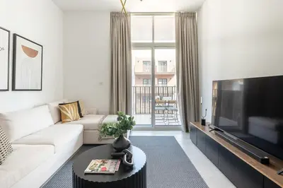 a living room with a white couch and a flat screen tv at Frank Porter - Belgravia 3 in Dubai