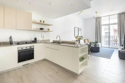 a white kitchen with a sink and a stove at Frank Porter - Belgravia 3 in Dubai
