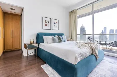 a bedroom with a blue bed and a large window at GuestReady - Skyview Home with Marina View in Dubai