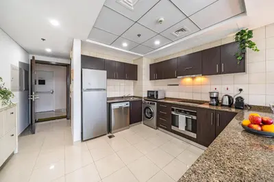 a large kitchen with brown cabinets and appliances at Cute 1BR - Dubai Marina Views - Walk 9min to Beach in Dubai