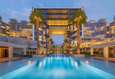 a large building with a swimming pool with palm trees at Maison Privee - Luxury Sea View Apt in FIVE Resort on The Palm in Dubai