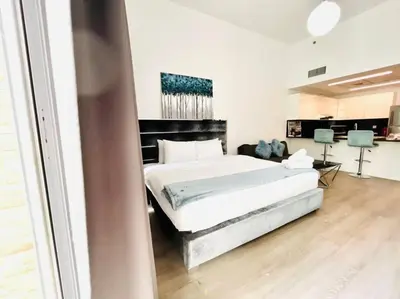 a bedroom with a large white bed in a room at ModernLux - Lovely Studio Apartment in JVT next to Park in Dubai