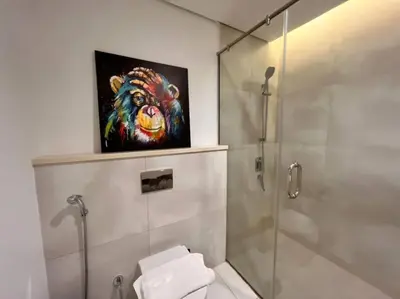 a bathroom with a shower and a painting of a monkey at ModernLux - Lovely Studio Apartment in JVT next to Park in Dubai