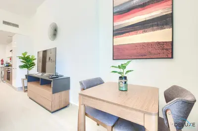 a living room with a table and chairs and a tv at Perfect Studio Getaway Next to the Iconic Creek Harbour, Azizi Aliyah, Al Jaddaf, by Deluxe Holiday Homes in Dubai