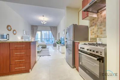 a kitchen with stainless steel appliances and a living room at Pleasant Studio at Safir Tower 1 Business Bay by Deluxe Holiday Homes in Dubai
